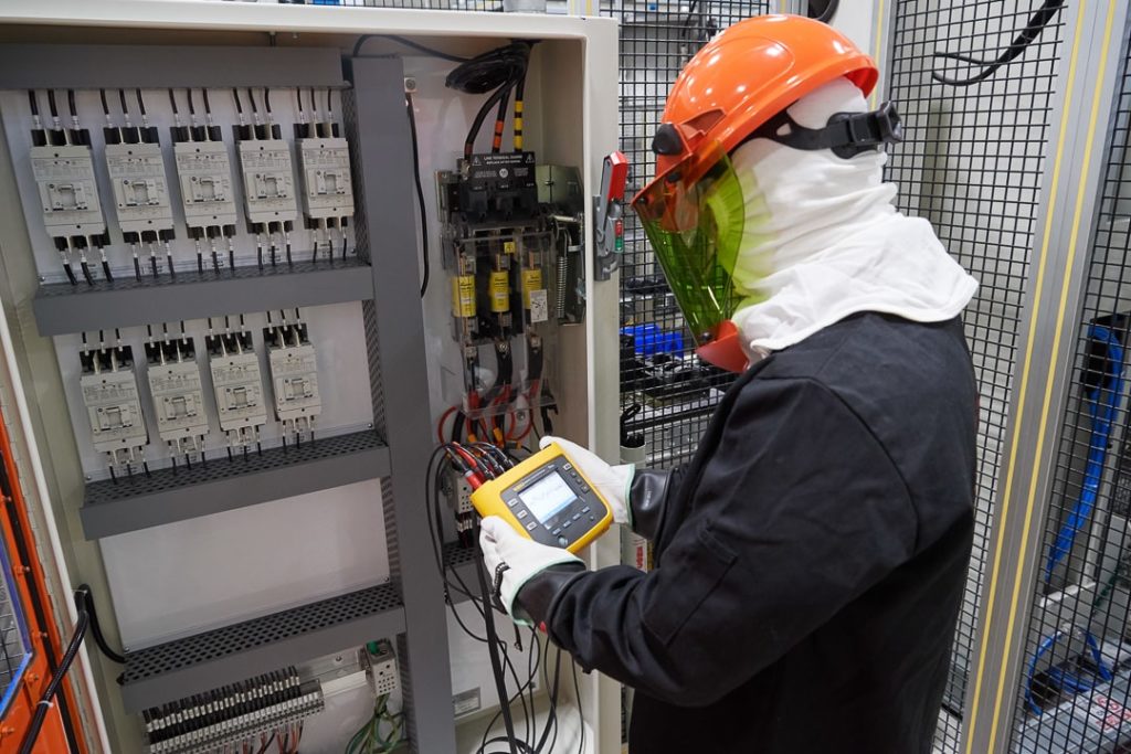 Worker conducting electrical testing using P-F Curve.