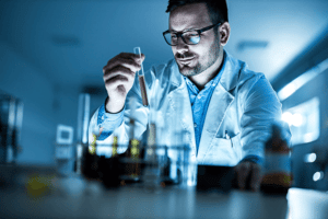 Scientist examining yellow liquid in glass vile